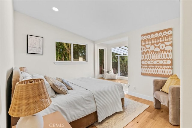 bedroom with vaulted ceiling and light hardwood / wood-style flooring