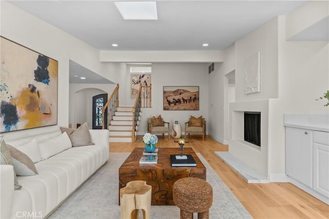 living room with a skylight and light hardwood / wood-style floors