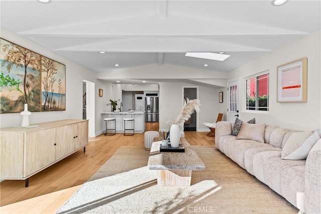 living room featuring light hardwood / wood-style floors and vaulted ceiling with skylight