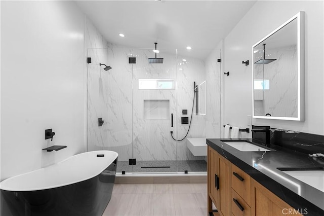 full bath with a sink, a marble finish shower, and a freestanding tub