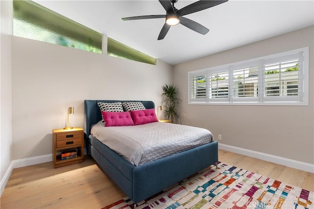 bedroom featuring ceiling fan, baseboards, wood finished floors, and vaulted ceiling