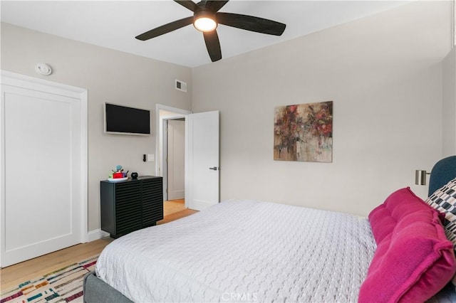 bedroom with visible vents, light wood-style flooring, a ceiling fan, and vaulted ceiling