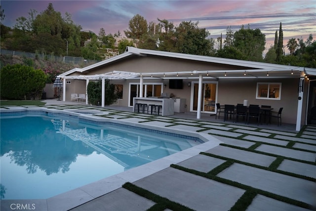 pool featuring outdoor dry bar, an outdoor kitchen, outdoor dining area, and a patio