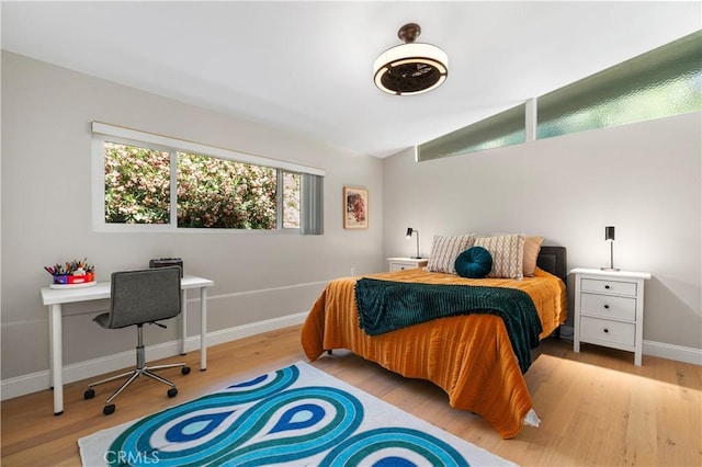 bedroom with lofted ceiling, wood finished floors, and baseboards