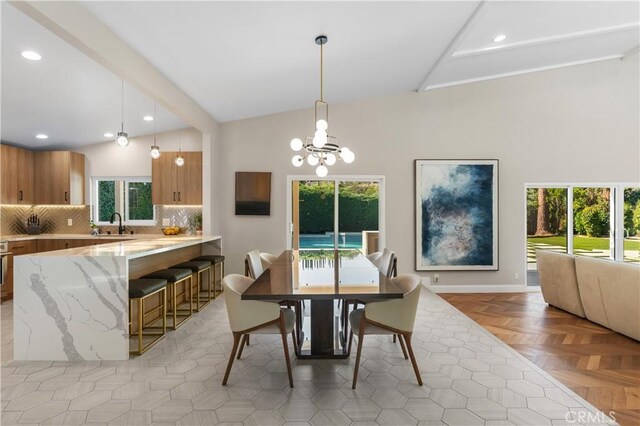 dining space with lofted ceiling with beams, light parquet floors, sink, and an inviting chandelier