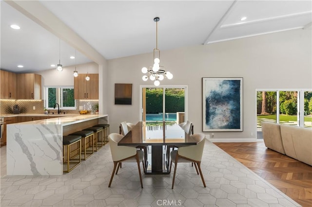 dining space with lofted ceiling with beams, light parquet flooring, sink, and a notable chandelier