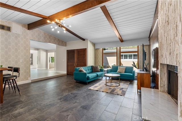 living area featuring visible vents, vaulted ceiling with beams, baseboards, a premium fireplace, and a notable chandelier