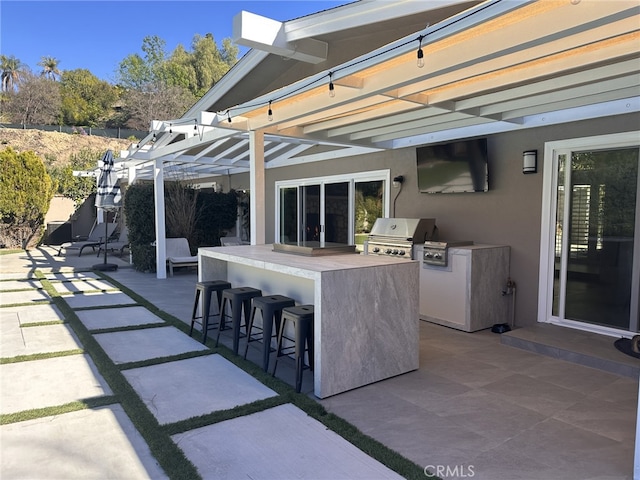 view of patio with outdoor wet bar, exterior kitchen, a pergola, and a grill