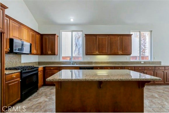 kitchen with black range with gas stovetop, a kitchen breakfast bar, and a kitchen island