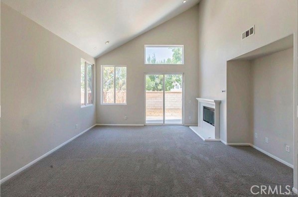 unfurnished living room featuring high vaulted ceiling and carpet