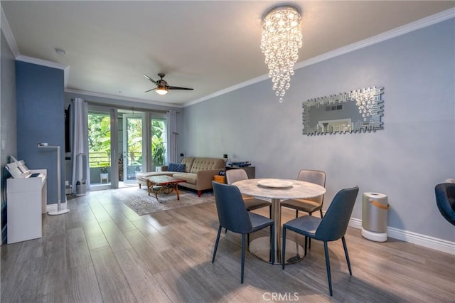 dining room featuring crown molding, hardwood / wood-style floors, and ceiling fan with notable chandelier