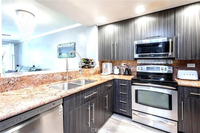 kitchen with tasteful backsplash, stainless steel appliances, light stone counters, and a sink