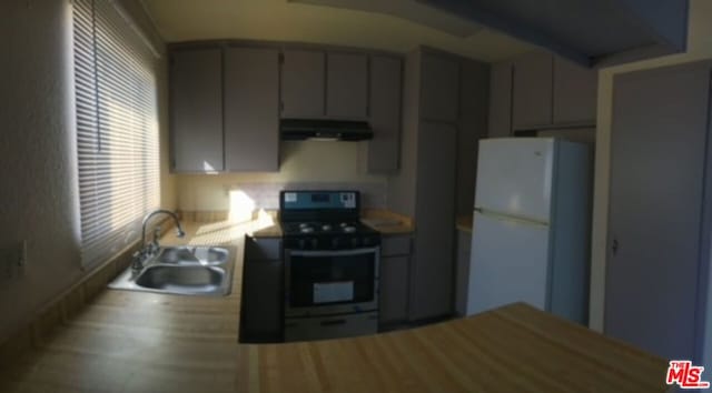 kitchen featuring white refrigerator, black electric range, sink, and gray cabinetry