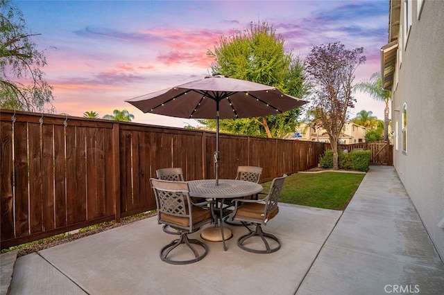 patio terrace at dusk featuring a lawn