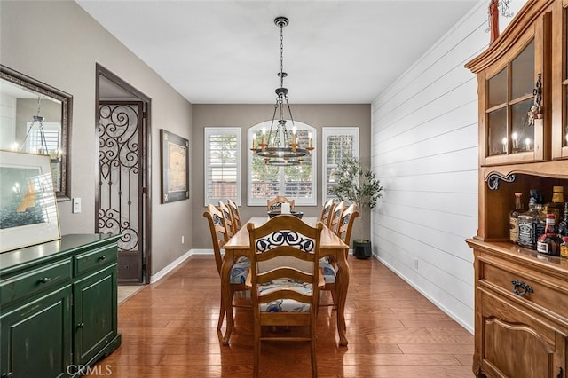 dining room featuring dark hardwood / wood-style floors, wood walls, and a chandelier