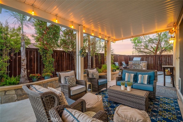 patio terrace at dusk featuring an outdoor hangout area and an outdoor kitchen