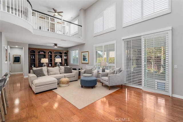 living room with a towering ceiling, plenty of natural light, hardwood / wood-style floors, and ceiling fan