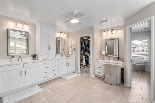 bathroom with ceiling fan, vanity, and a textured ceiling