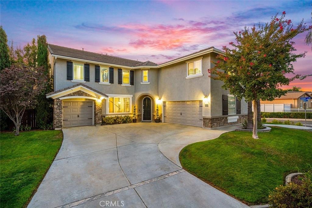view of front of house featuring a lawn, concrete driveway, stone siding, a garage, and stucco siding