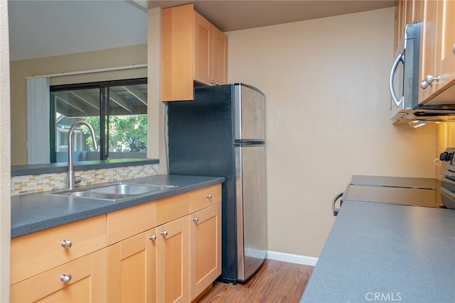 kitchen with light wood-type flooring, sink, decorative backsplash, light brown cabinets, and appliances with stainless steel finishes