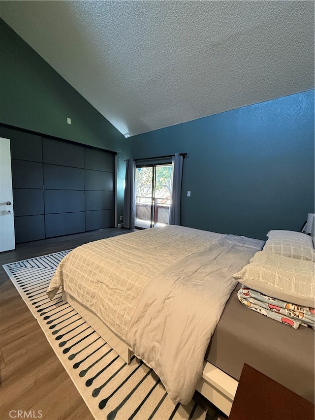 bedroom with hardwood / wood-style flooring, vaulted ceiling, and a textured ceiling