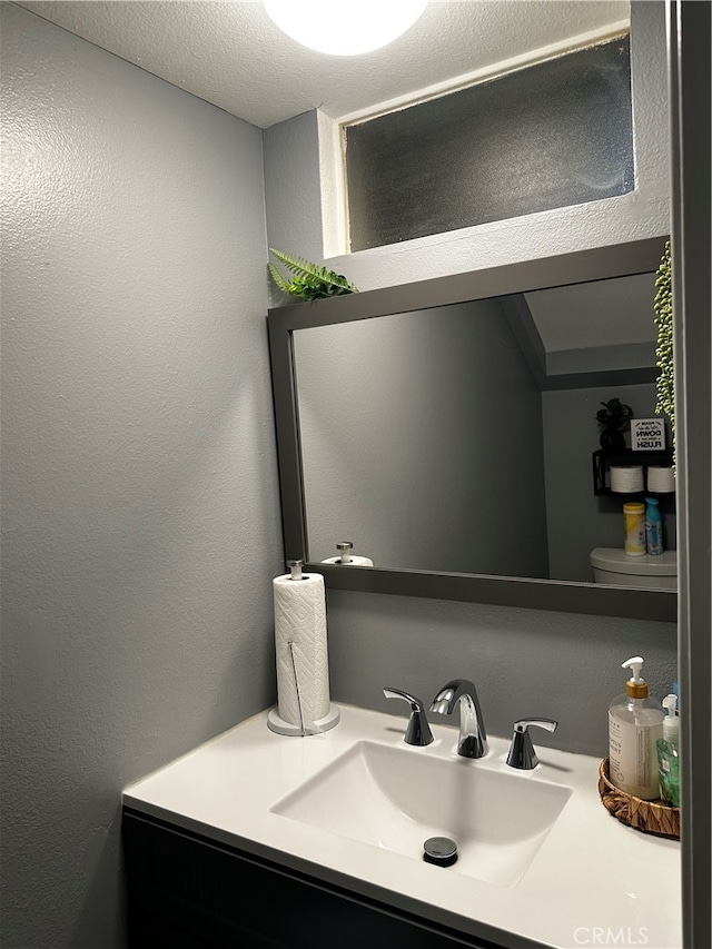 bathroom featuring a textured ceiling, vanity, and toilet