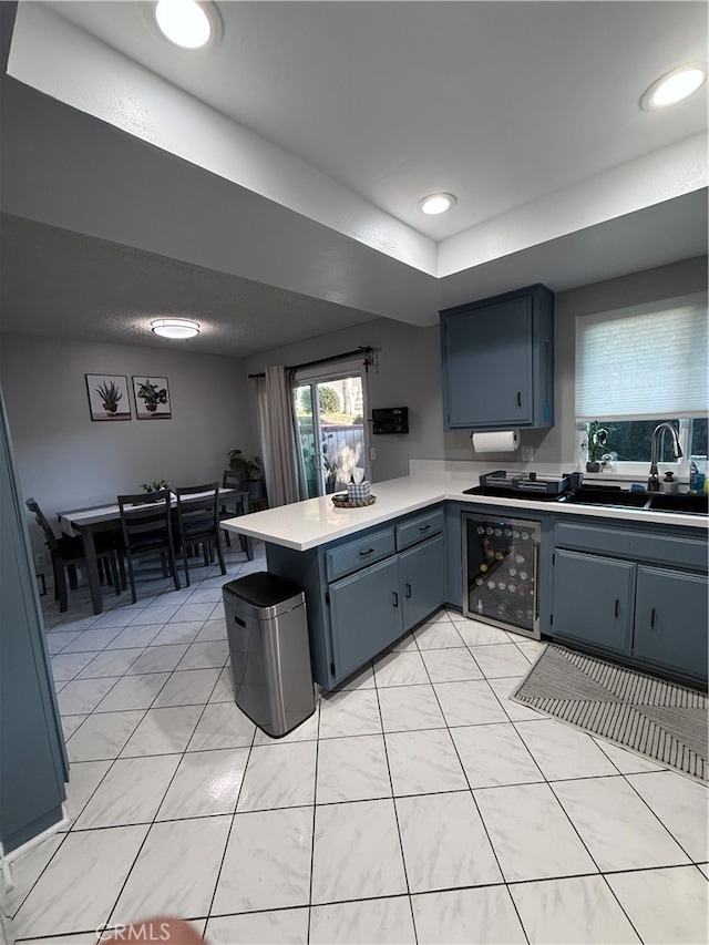 kitchen featuring kitchen peninsula, light tile patterned floors, and sink