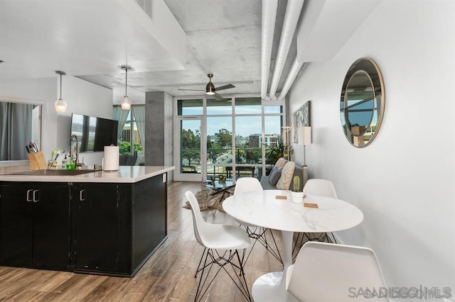 kitchen with ceiling fan, sink, light hardwood / wood-style floors, a wall of windows, and hanging light fixtures