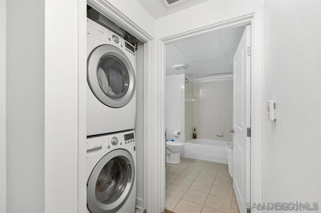 laundry area with light tile patterned floors and stacked washer / drying machine