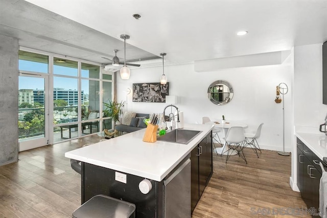 kitchen with pendant lighting, a kitchen island with sink, sink, and dark hardwood / wood-style floors