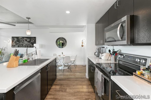 kitchen featuring appliances with stainless steel finishes, hanging light fixtures, sink, and wood-type flooring