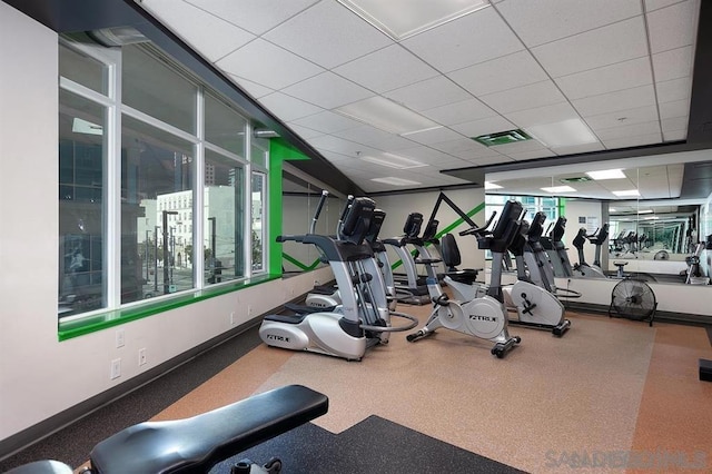 gym with a drop ceiling and a healthy amount of sunlight