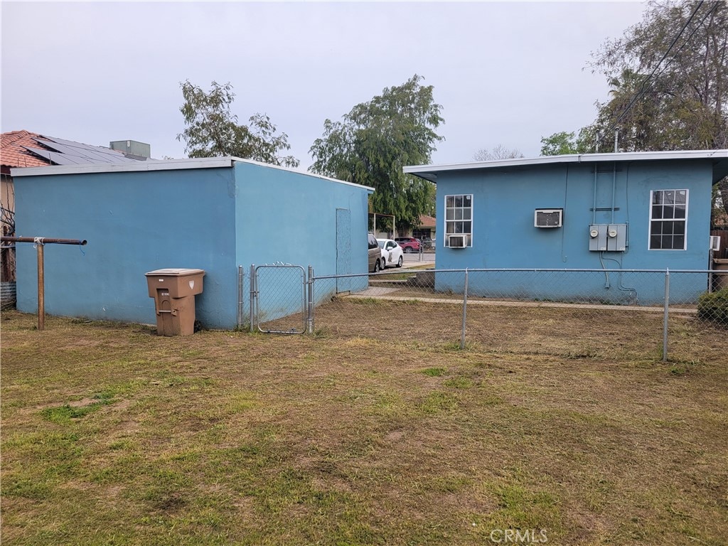 view of property exterior with a wall mounted AC and a yard