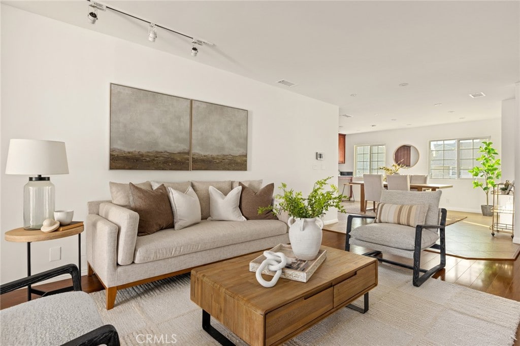 living room featuring rail lighting and light hardwood / wood-style flooring