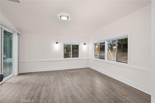 unfurnished room with lofted ceiling and hardwood / wood-style floors