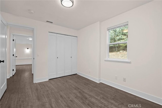 unfurnished bedroom with dark hardwood / wood-style flooring and a closet