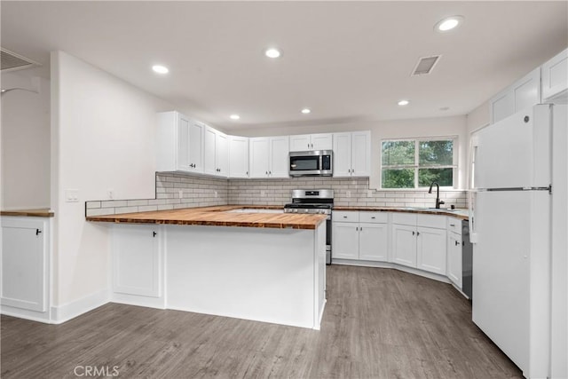 kitchen with butcher block countertops, appliances with stainless steel finishes, sink, and white cabinetry