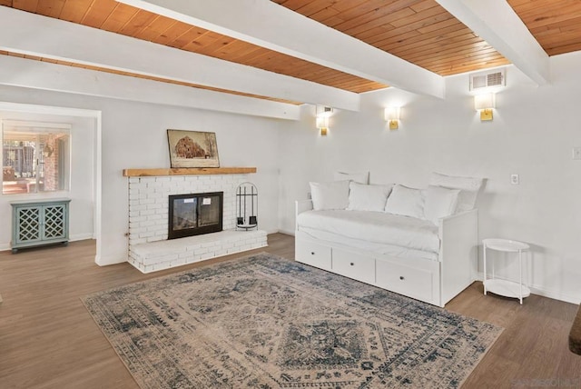 living room featuring a brick fireplace, beamed ceiling, dark wood-type flooring, and wooden ceiling