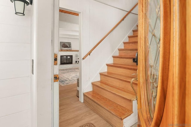 staircase featuring a brick fireplace and wood-type flooring