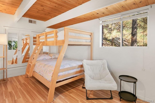 bedroom with beam ceiling, hardwood / wood-style flooring, and wooden ceiling