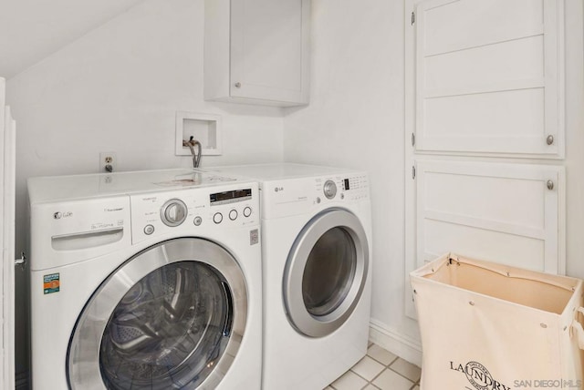 laundry room with washing machine and dryer, light tile patterned flooring, and cabinets