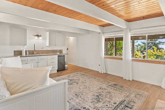 living room with light hardwood / wood-style flooring, beam ceiling, wooden ceiling, and sink