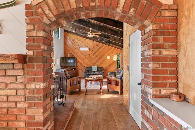 interior space with vaulted ceiling with beams, hardwood / wood-style flooring, and wooden walls