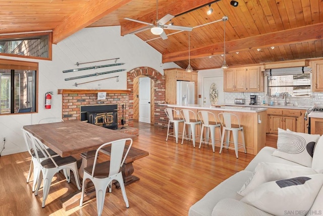 dining area with light wood-type flooring, sink, a wood stove, and a wealth of natural light