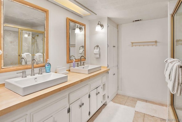 bathroom featuring tile patterned flooring, vanity, and a shower with door