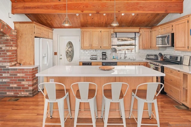 kitchen with light hardwood / wood-style floors, appliances with stainless steel finishes, hanging light fixtures, and sink