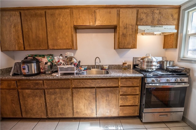 kitchen featuring light tile patterned floors, stainless steel gas range oven, and sink