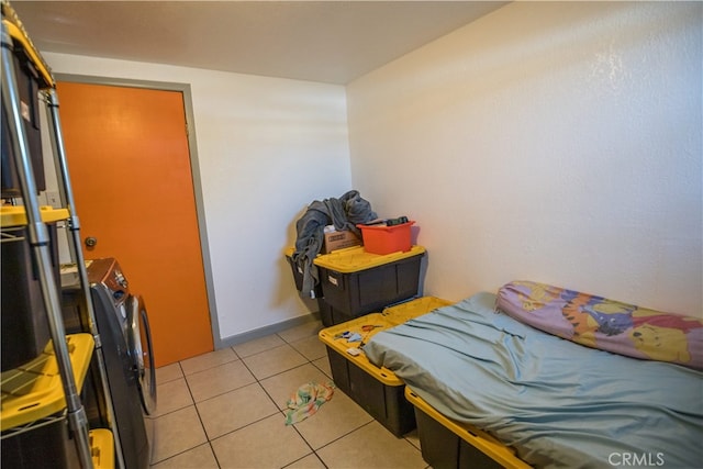 bedroom with separate washer and dryer and light tile patterned floors