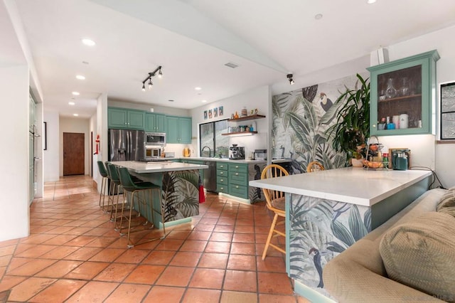 kitchen with a breakfast bar, light tile patterned floors, stainless steel appliances, and vaulted ceiling