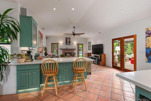 kitchen with light tile patterned floors, vaulted ceiling, ceiling fan, a breakfast bar, and green cabinets